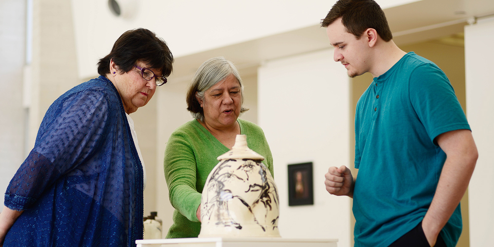 Three people look at a covered urn.