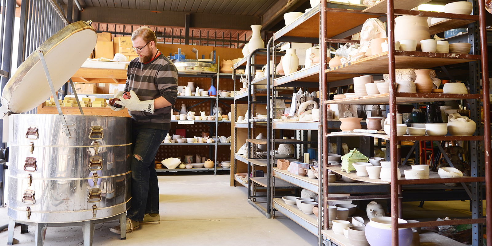 A pottery room with racks of pots and a kiln.