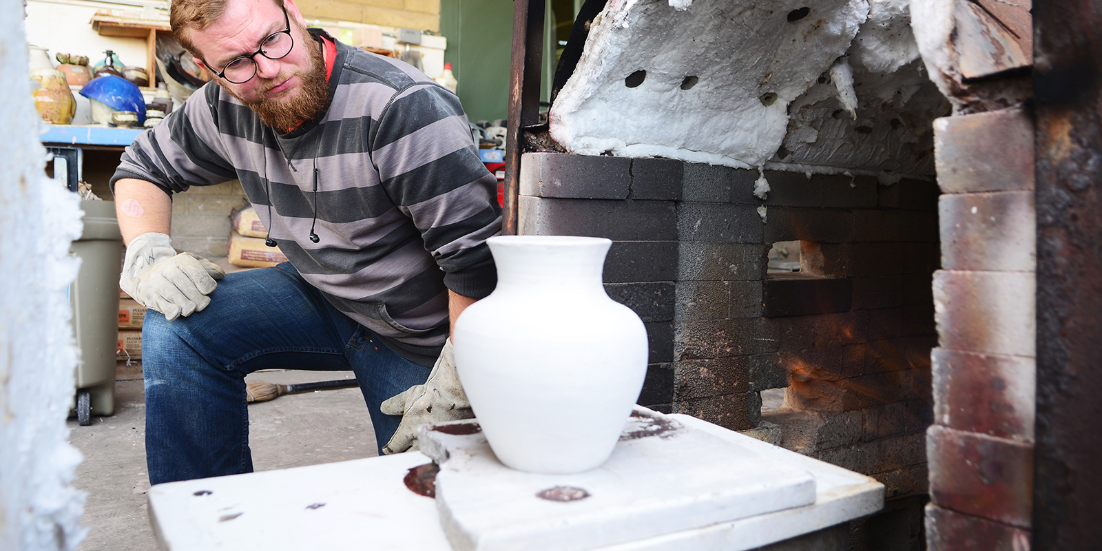 A man inspected an unfired pot.