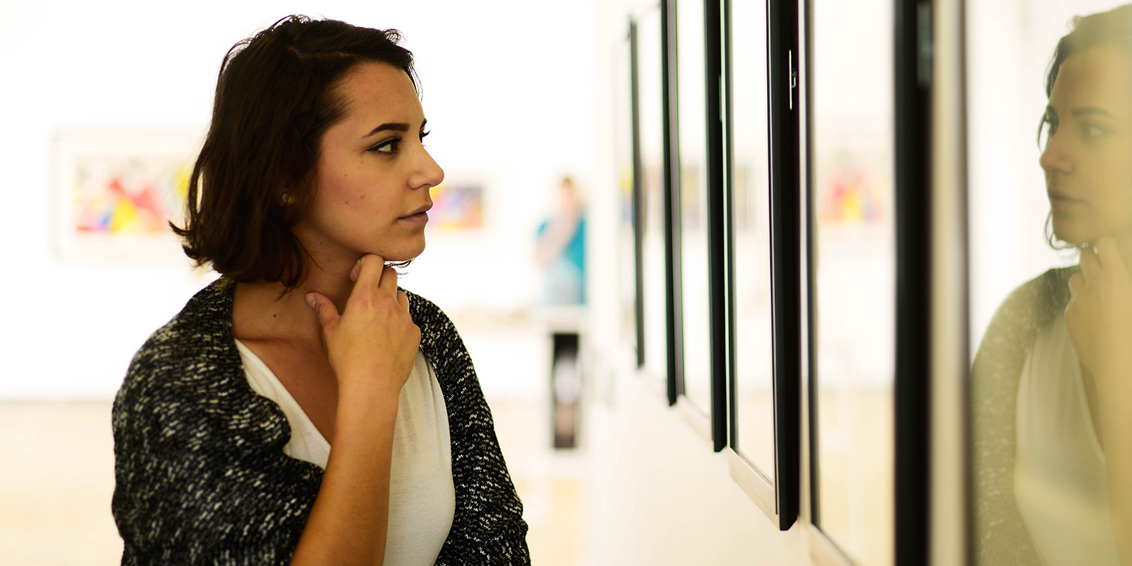 A woman looking at hanging paintings.