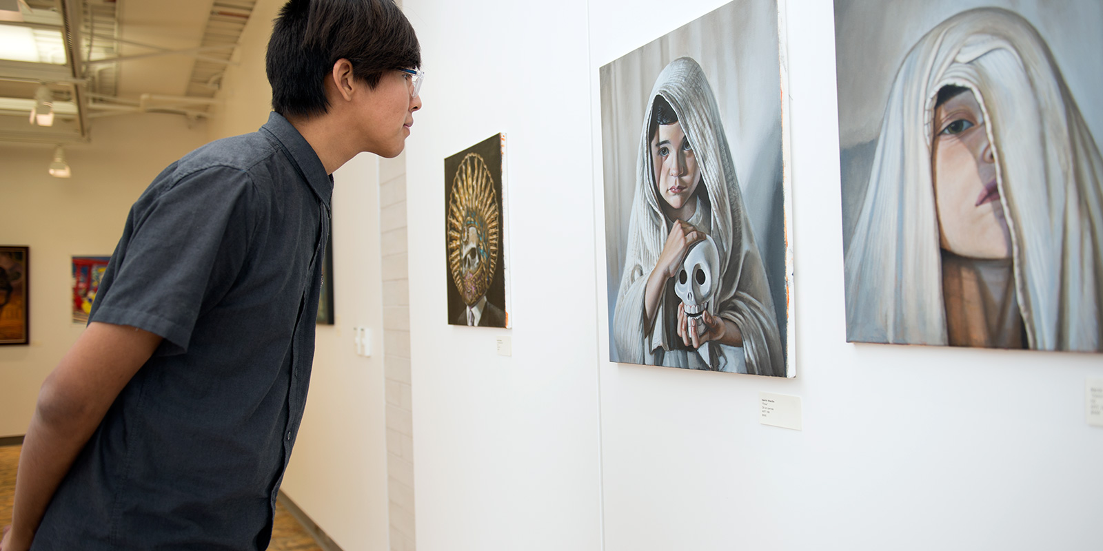A man viewing a painting of a child and skull.