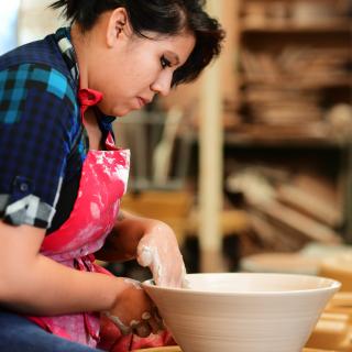 A student forming a pot out of clay.