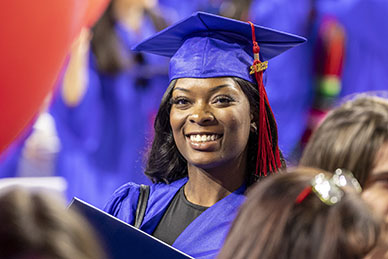 A graduate smiles in the crowd at graduation