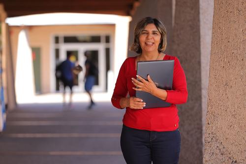 An employee holding a laptop outside.