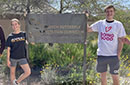 Two students stand next to a sign: Monarch Butterfly Waystation Corridor