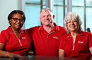 Three alumni in MCC polo shirts smiling