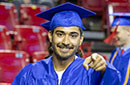 A student in a cap and gown points at the camera