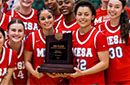 A group of women's basketball players with two holding a trophy