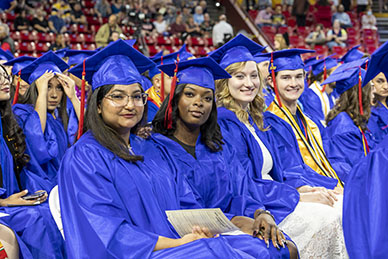 Four graduate seated in a row at the graduation ceremony