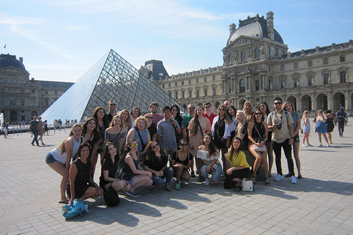 Students pose in front of the Louvre glass pyramid in Paris