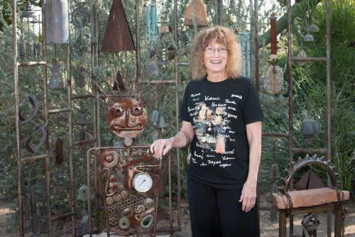 Carole Drachler in front of an outdoor display of metal art and windchimes